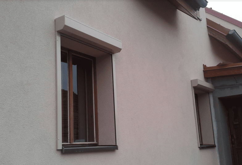 Předokenní venkovní hliníková roleta v béžové barvě ladí s fasádou domu