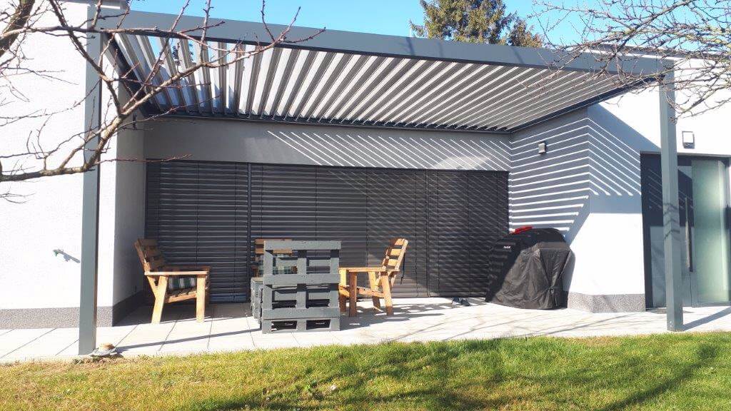 Minimalistick&aacute; pergola zasazen&aacute; do v&yacute;klenku domu. &Scaron;irok&aacute; přes 5 metrů, s jedn&iacute;m motorem